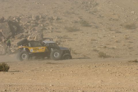 1992 Jeep Wrangler - A yellow off-road buggy navigates a dusty desert terrain during a race.