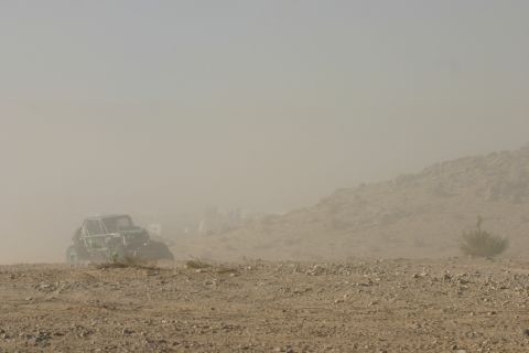 1992 Jeep Wrangler - A buggy races across a dusty, rocky landscape under a hazy sky.