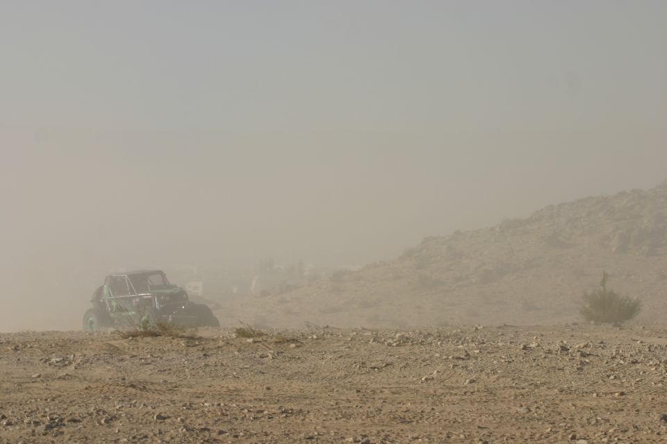 Buggy kicking up dust on a rocky desert terrain