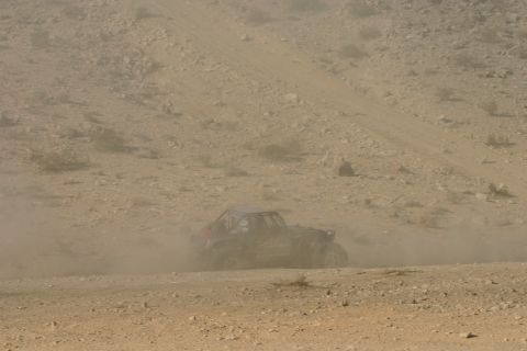 1992 Jeep Wrangler - A buggy races through a dusty desert landscape, its tires kicking up a cloud of dirt.