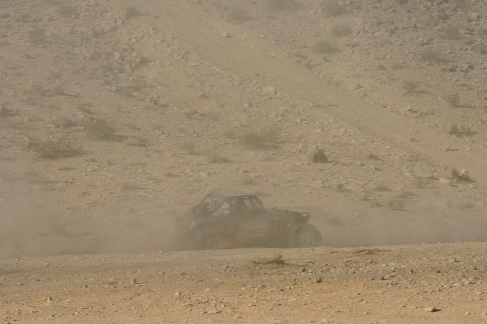 Off-road buggy kicking up dust on a desert track