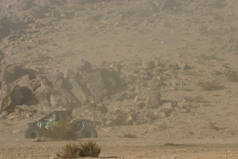 1992 Jeep Wrangler - Off-road buggy navigates a dusty desert course with rocky inclines in the background.
