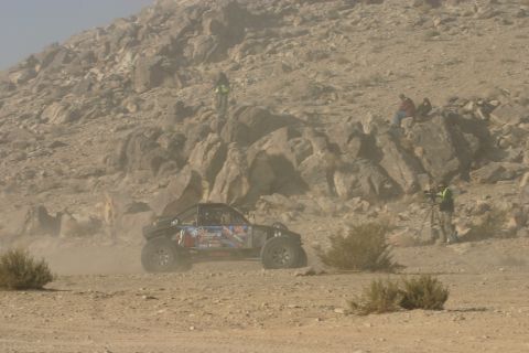 1992 Jeep Wrangler - A custom off-road buggy races through a dusty, rocky terrain with spectators watching from the hillsides.