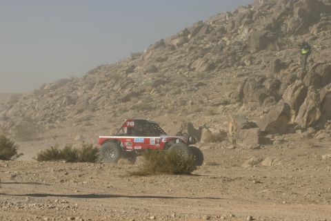 1992 Jeep Wrangler - Off-road buggy competes in a desert race, kicking up dust on a rocky course.