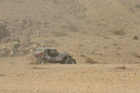 1992 Jeep Wrangler - Off-road buggy competes in a desert race, dust trails behind it as it navigates the terrain.
