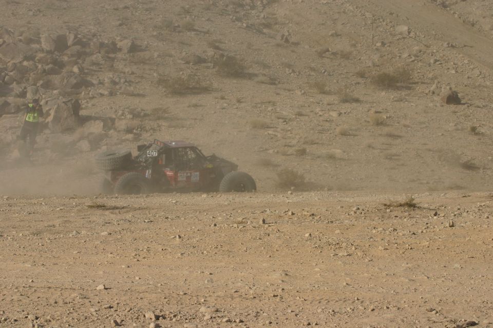 Off-road buggy kicking up dust on a desert course. Number 407 is visible on the side
