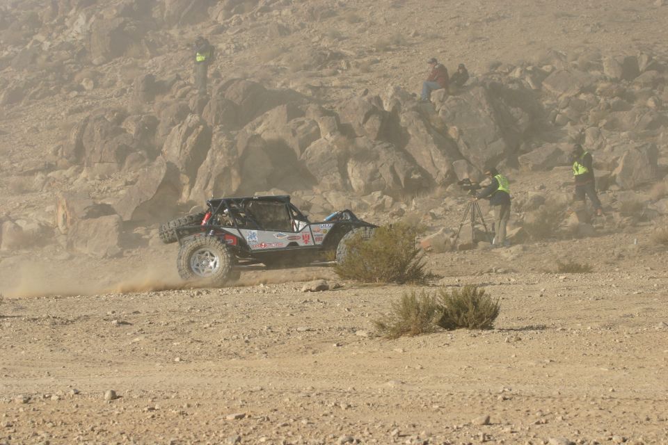 Off-road buggy with roll cage driving on dusty terrain