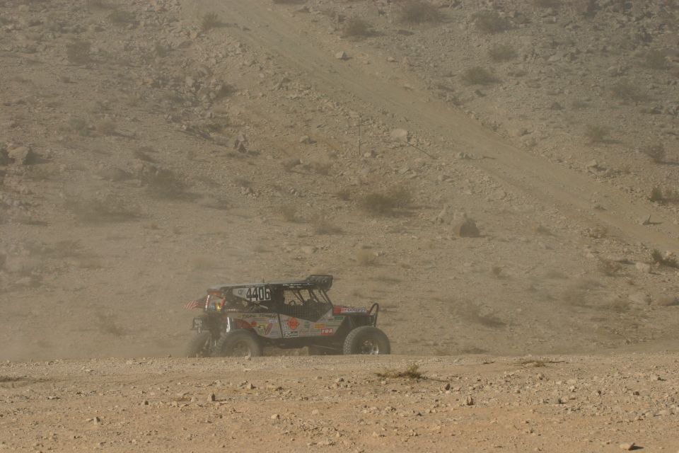 Off-road buggy with number 4406 on side kicks up dust on a dirt track