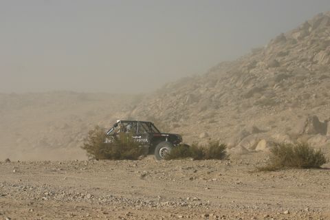1992 Jeep Wrangler - Off-road buggy navigates a dusty desert landscape, kicking up dust.