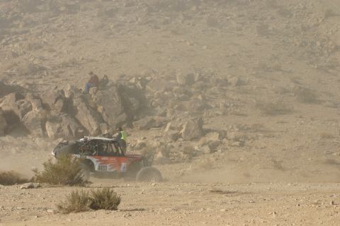 1992 Jeep Wrangler - A buggy races through a dusty desert landscape with spectators watching from a rocky outcrop.