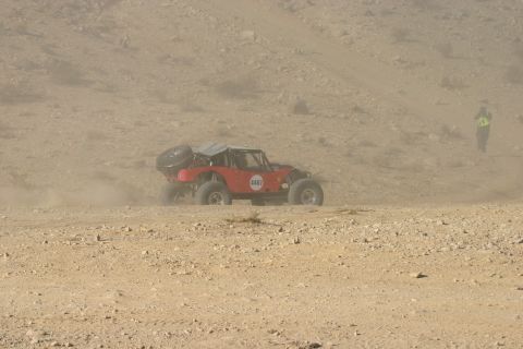 1992 Jeep Wrangler - A red buggy races across a dusty, arid landscape with a person in a safety vest observing.