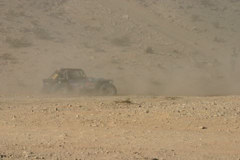 1992 Jeep Wrangler - An off-road buggy races across a dusty desert terrain, kicking up a cloud of dust behind it.