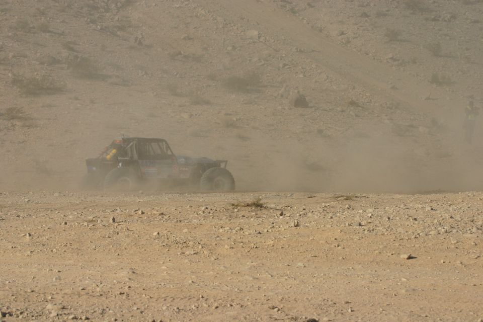 Off-road buggy racing through dust, side view