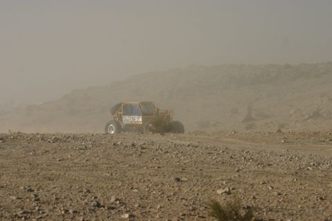 1992 Jeep Wrangler - A yellow off-road buggy navigates a dusty, rocky landscape under a hazy sky.