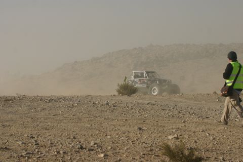 1992 Jeep Wrangler - An off-road buggy navigates a dusty terrain during an event, observed by a person in a safety vest.