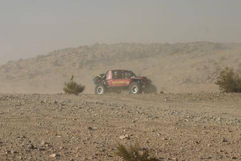 1992 Jeep Wrangler - A custom-built off-road buggy navigates a dusty desert course, kicking up dust as it goes.