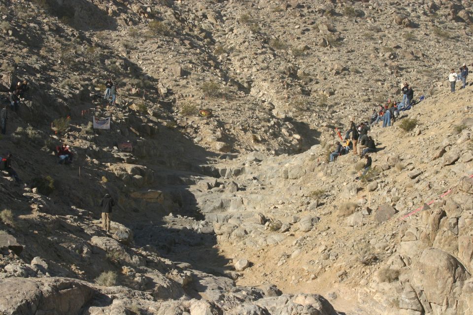 Spectators gathered on a steep, rocky slope watching an off-road event