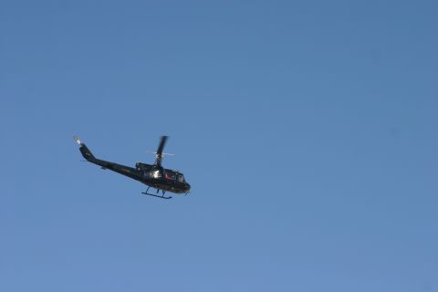 1992 Jeep Wrangler - A dark helicopter is captured in mid-air against a vast expanse of blue sky.