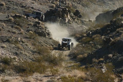 1992 Jeep Wrangler - Two off-road vehicles navigate a challenging desert course, kicking up significant dust.