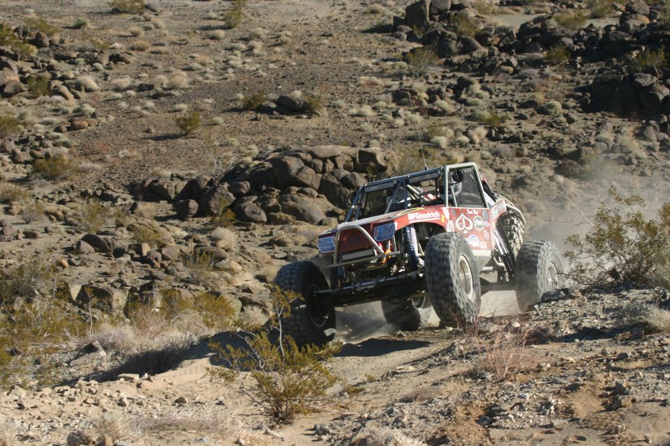 Custom off-road buggy with large tires climbing a dusty, rocky incline. BFGoodrich tire branding visible