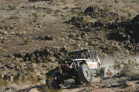 1992 Jeep Wrangler - A heavily modified off-road buggy navigates a challenging rocky terrain during a race.