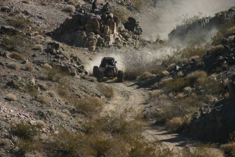 1992 Jeep Wrangler - An off-road buggy navigates a dusty trail in a rocky, arid landscape.