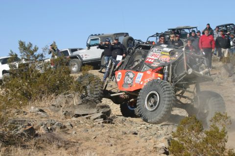 1992 Jeep Wrangler - Multiple off-road vehicles and spectators gather on a rocky terrain under a clear blue sky.