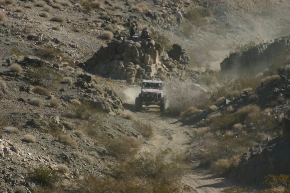 Off-road vehicle kicking up dust on a rocky, desert trail