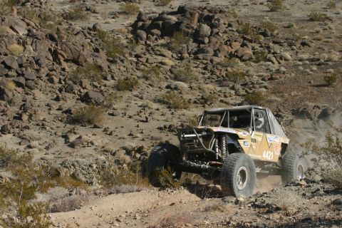 1992 Jeep Wrangler - A custom off-road buggy kicks up dust as it maneuvers through a challenging desert landscape.