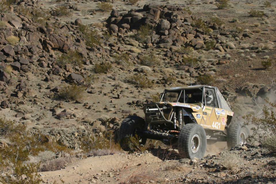 Yellow off-road buggy with large tires navigating a rocky desert terrain