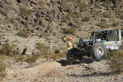 1992 Jeep Wrangler - Off-road buggy with safety vest wearer in desert terrain. The vehicle has racing decals and the number 302.