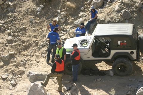 1992 Jeep Wrangler - A group of people gather around a silver Jeep Wrangler on a rocky, off-road trail.
