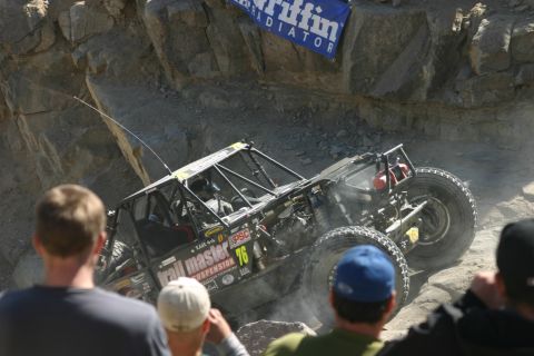 1992 Jeep Wrangler - A modified off-road buggy with a roll cage and large tires navigates a steep, rocky incline during an event.