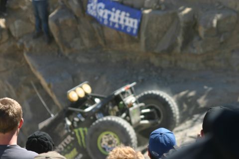 1992 Jeep Wrangler - A souped-up off-road buggy navigates a challenging rocky terrain during a competition, observed by a crowd.
