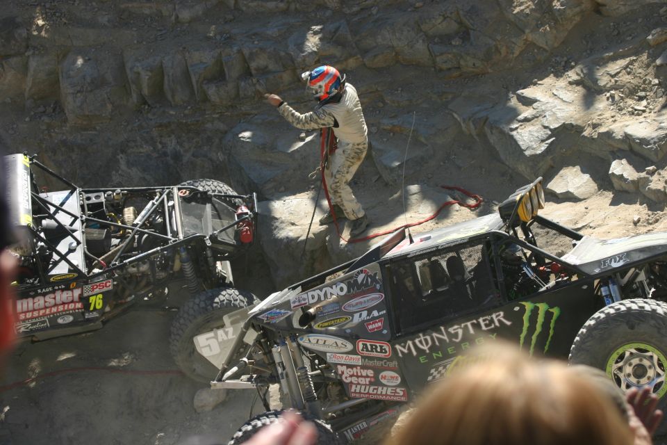 Off-road race vehicles in a rocky canyon, one with Monster Energy branding
