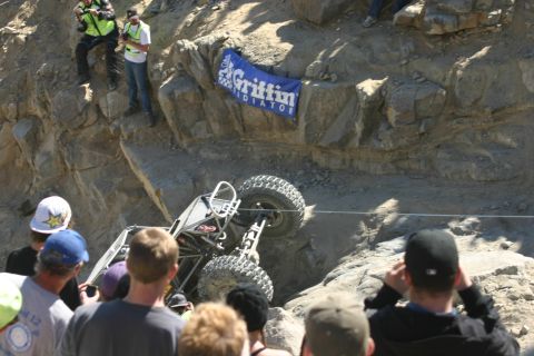 1992 Jeep Wrangler - A custom off-road vehicle is stuck on a steep, rocky incline while onlookers observe the difficult situation.