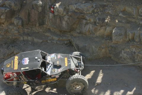 1992 Jeep Wrangler - An off-road buggy navigates a steep, rocky terrain during an event.