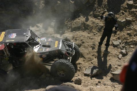 1992 Jeep Wrangler - A driver navigates a challenging off-road course, kicking up dust as they ascend a steep, rocky incline.