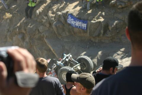 1992 Jeep Wrangler - An off-road vehicle is seen tilted on a rocky incline during an event, with onlookers observing the scene.