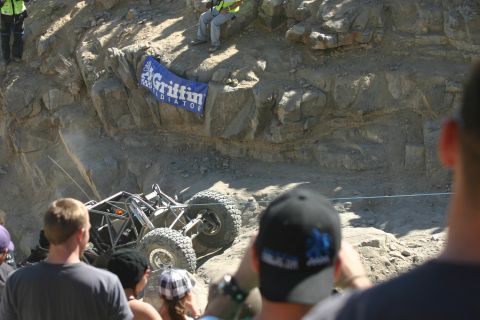 1992 Jeep Wrangler - An off-road buggy navigates a challenging rocky terrain during an event, with spectators observing.