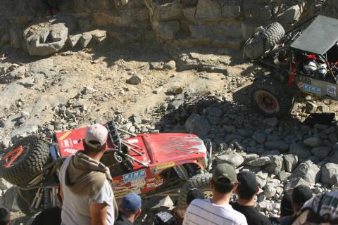 1992 Jeep Wrangler - Two off-road vehicles navigate a rocky terrain during an event, with one vehicle overturned.
