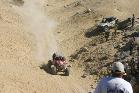 1992 Jeep Wrangler - Two off-road vehicles navigate a steep, sandy terrain during an event.