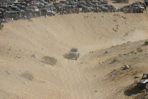1992 Jeep Wrangler - Off-road buggy navigates a steep sandy slope during an event, spectators watch from the ridge.