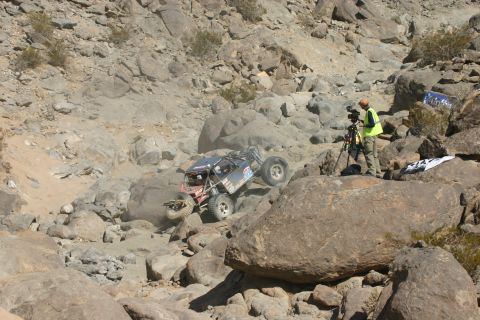 1992 Jeep Wrangler - A custom off-road vehicle navigates a challenging rocky terrain while a cameraman documents the action.