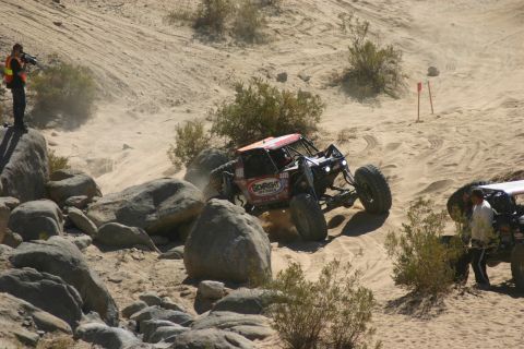 1992 Jeep Wrangler - Two off-road vehicles tackle a challenging sandy and rocky course during an event.