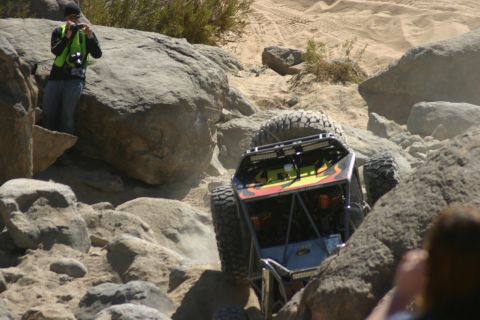 1992 Jeep Wrangler - A custom buggy navigates a challenging rocky terrain, kicking up dust as it climbs.