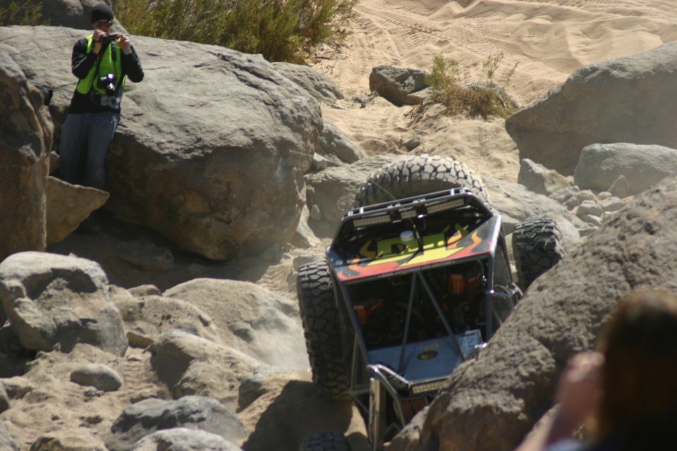 Rear view of a custom off-road buggy with flame graphics climbing over large rocks