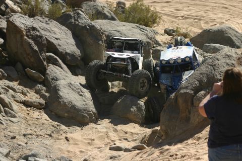 1992 Jeep Wrangler - Two custom off-road vehicles tackle a challenging rocky course during an event.