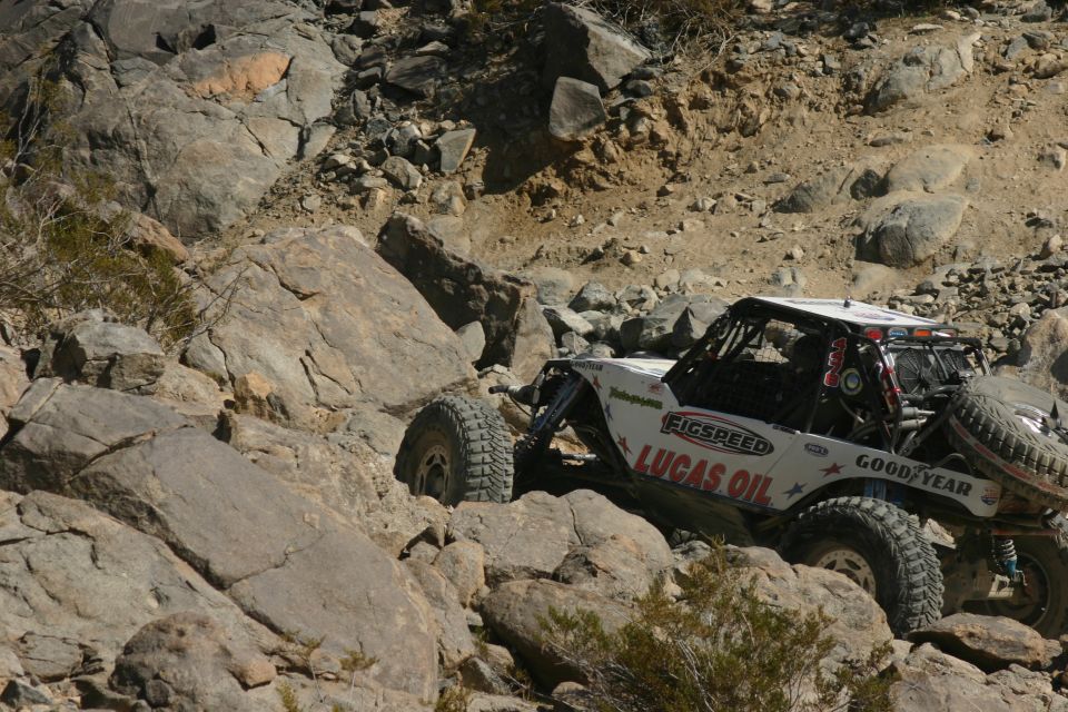 White off-road buggy with 'Lucas Oil' and 'Goodyear' decals navigating rocky terrain