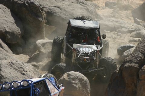 1992 Jeep Wrangler - Two off-road buggies navigate a rocky course, kicking up dust.
